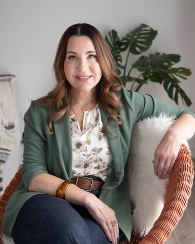 Shelley Heavens sitting in a wicker chair, smiling